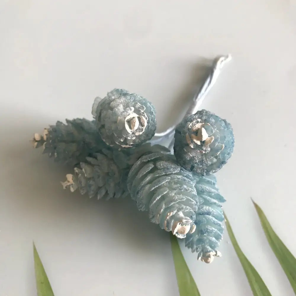 A pastel pinecone artificial flower wreath featuring frosted blue and metallic silver accents for living room decor