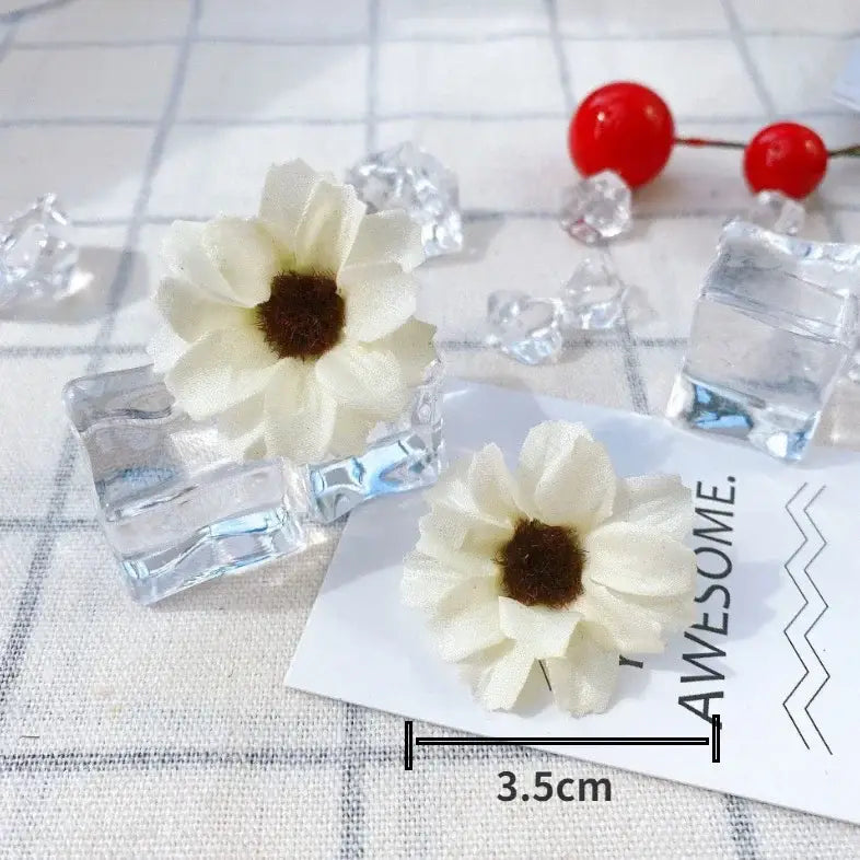 Cream-colored fabric mini daisy artificial earrings with brown centers displayed on white card for decorbites mini daisy use