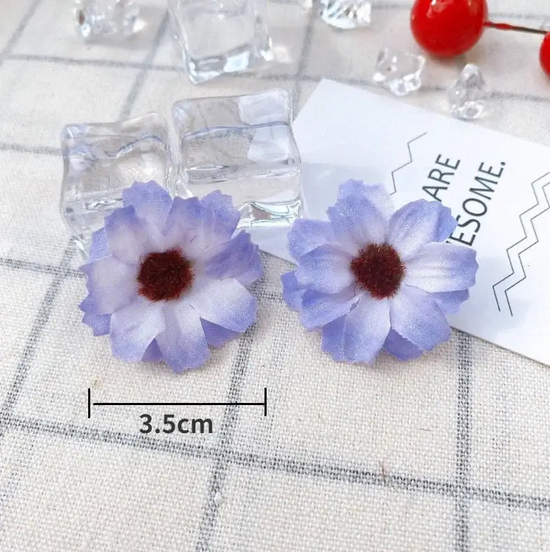 A pair of delicate lavender and white fabric mini daisy artificial flowers earrings with dark brown centers decorbites mini daisy