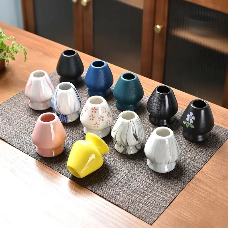 Pastel pink and yellow ceramic matcha whisk stand set featuring assorted mushroom-shaped tea bowl holder vases in solid and patterned hues