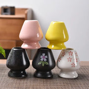 Set of four ceramic matcha whisk stand vases in pastel pink, bright yellow, matte black floral, and white red flower patterns