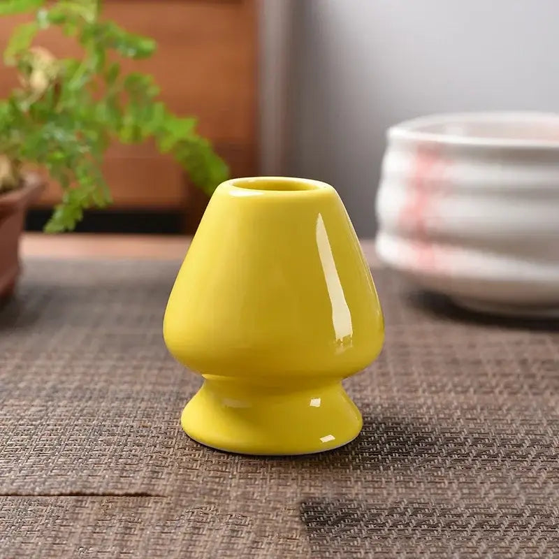 A glossy yellow ceramic matcha whisk stand with a flared top and rounded base for tea bowl holder use