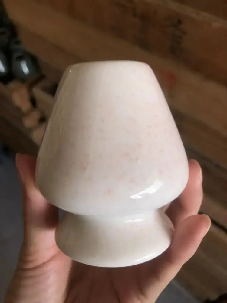 A smooth off-white ceramic matcha whisk stand with subtle speckled texture and classic tapered shape for tea bowl holder