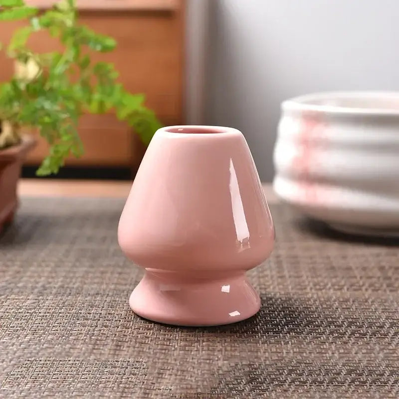 A smooth glossy pastel pink ceramic matcha whisk stand with flared top and rounded base for tea bowl holder use