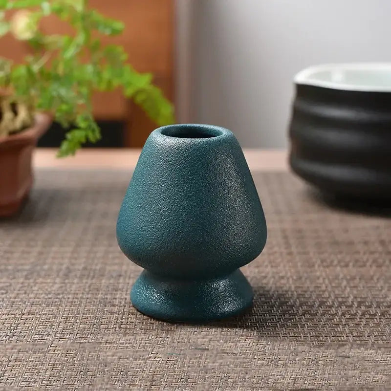 Teal ceramic tea scoop with textured matte finish and flared top in pastel pink and yellow matcha whisk stand set