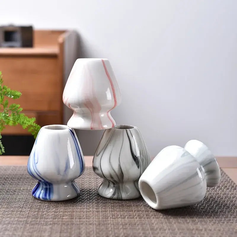 Pastel pink and yellow ceramic matcha whisk stand set with white ceramic vases featuring pink blue and gray marbled patterns