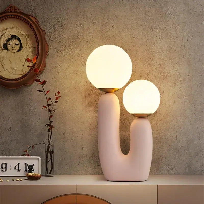 Pastel pink glass ball table lamp with dual glowing spherical shades and gold-toned accents for bedroom use