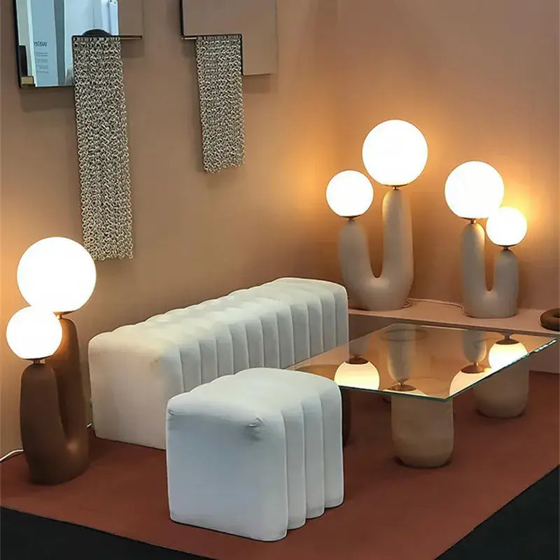 Modern white tufted sofa with ribbed upholstery paired with pastel pink glass ball table lamp with dual glowing spheres