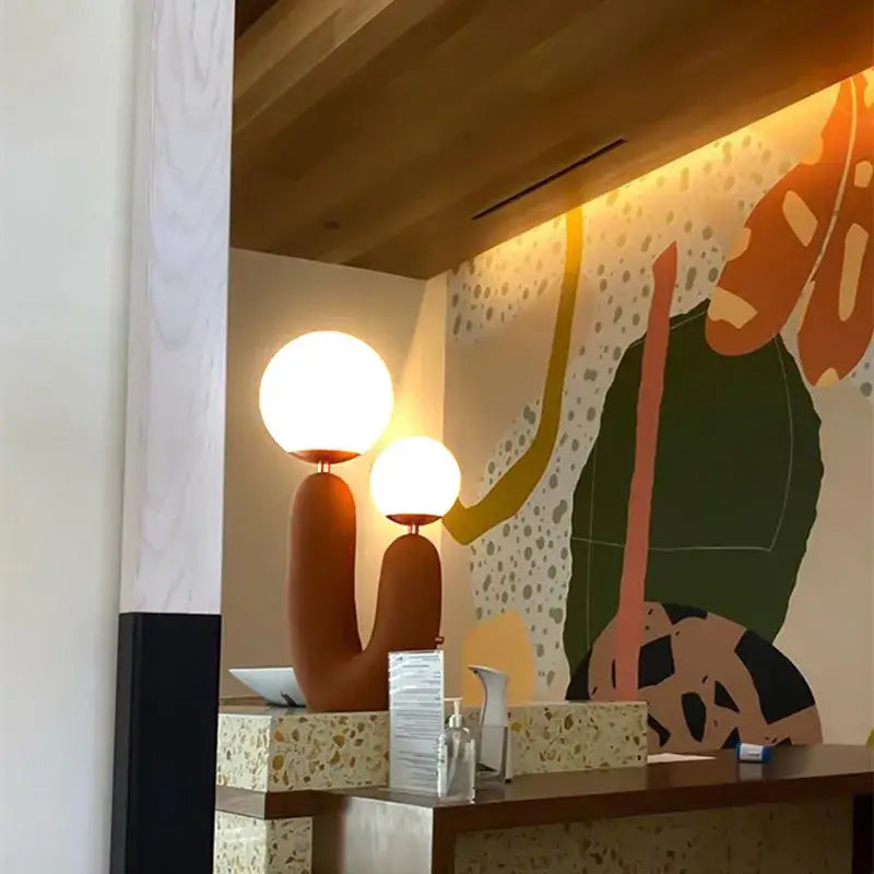 Two modern ball table lamps with warm glowing pastel pink glass ball shades and terracotta ceramic bases for bedrooms