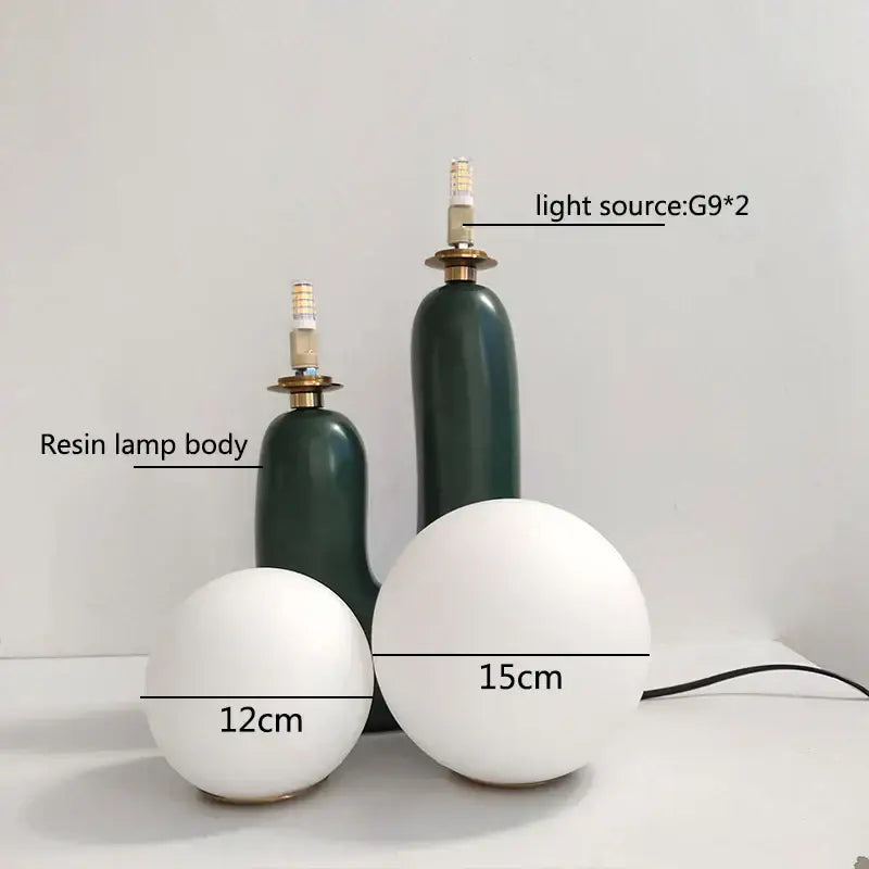 Two matte white spherical resin ball table lamps with dark green bases for bedroom use in pastel pink glass ball table style