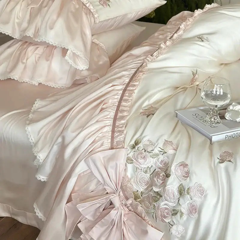 Pastel pink satin bedding set with delicate lace trim and ruffle flower embroidery in luxury lyocell fabric