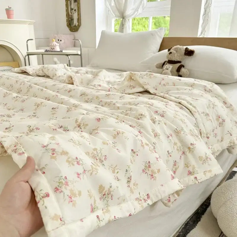 A soft cream-colored summer quilt with pastel pink and green floral pattern and decorbites cartoon bear printed design