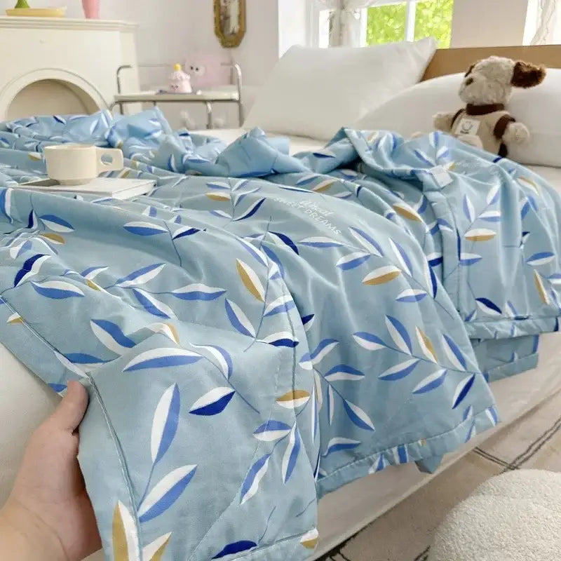Light blue quilted blanket with stylized leaves pattern on the back of pastel pink and white decorbites cartoon bear printed summer quilt