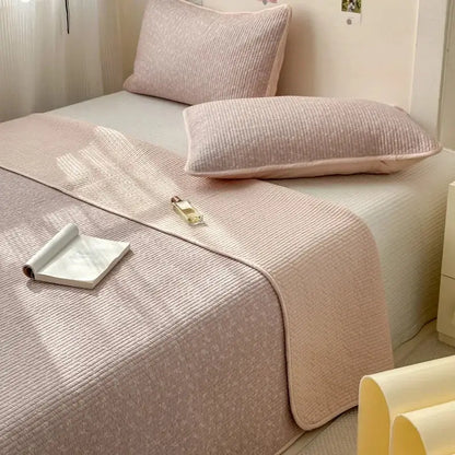 A soft blush pink cotton bed cover with a quilted textured pattern designed for use as a tatami mat