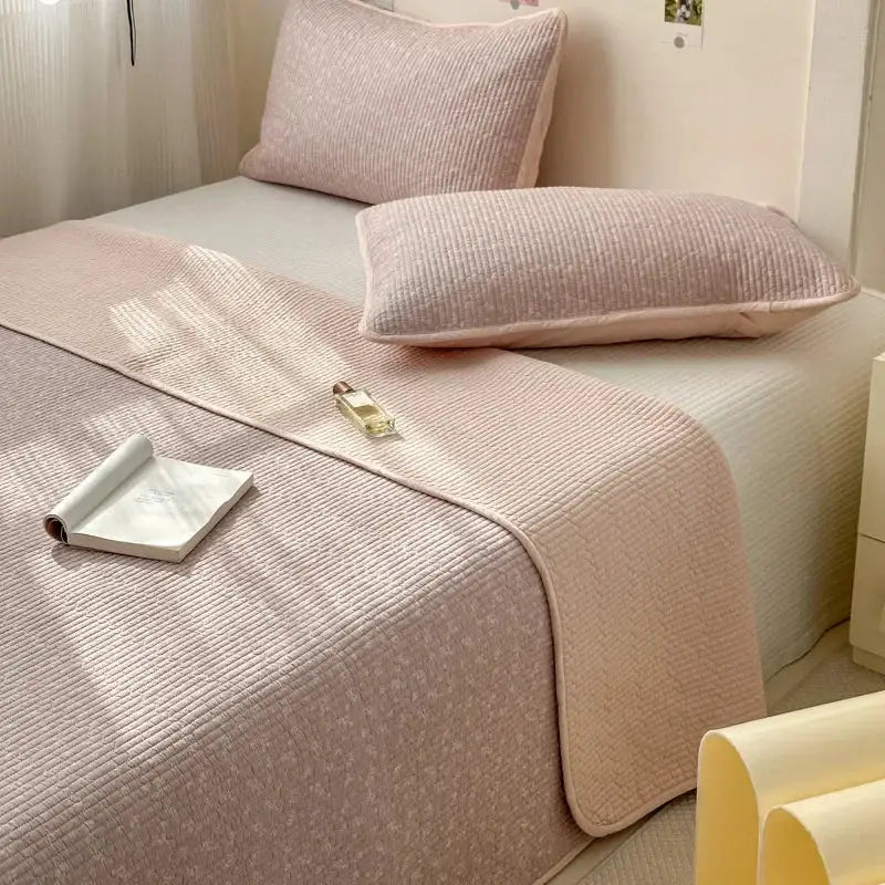 A soft blush pink cotton bed cover with a quilted textured pattern designed for use as a tatami mat