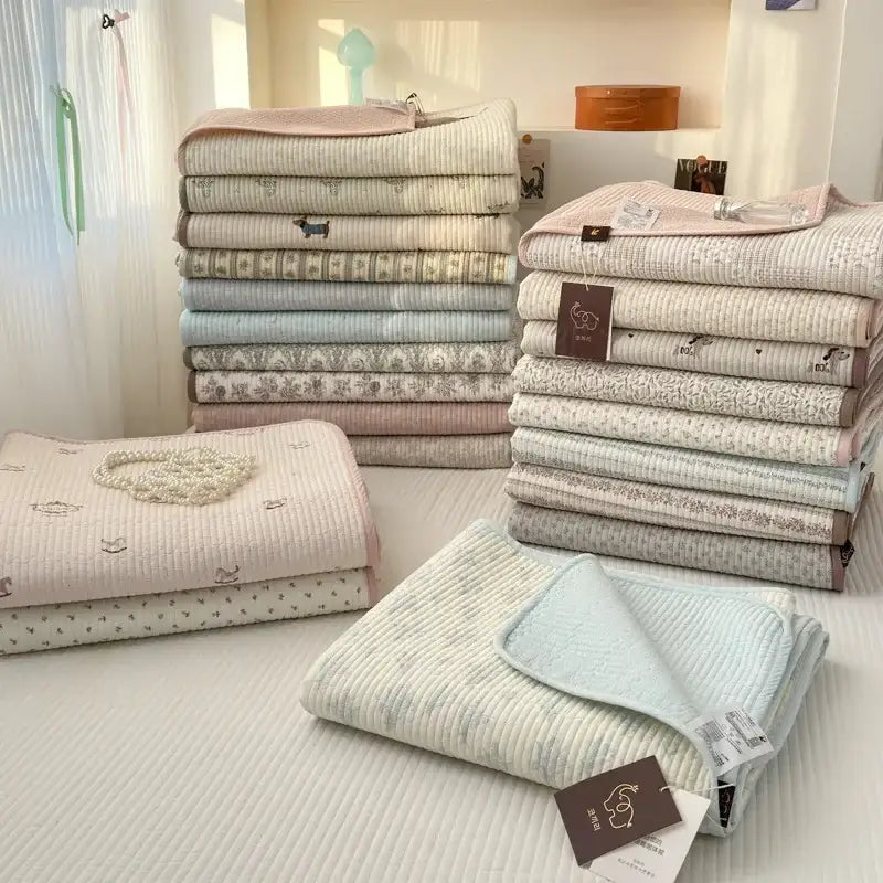 Stacks of soft pastel-colored quilted cotton bed covers with stitched textures for tatami mat and bedroom use