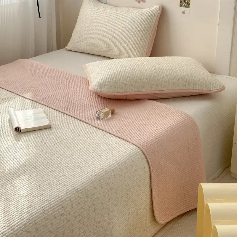 A soft pink and cream cotton bed cover with ribbed texture used as an anti-slip tatami mat bed runner