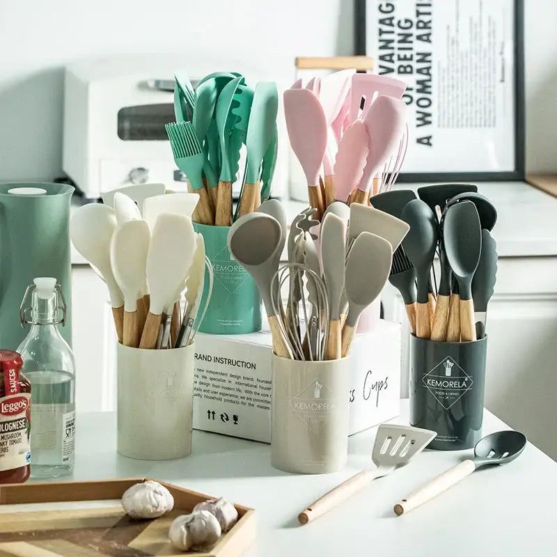 Set of pastel silicone kitchen utensils with wooden handles neatly organized in ceramic cups kitchen utensils set