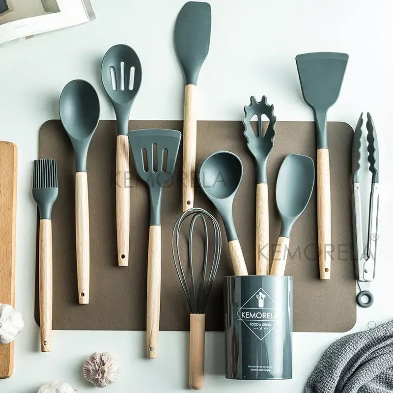 Set of gray silicone kitchen utensils with wooden handles and matching cylindrical storage canister in ceramic cup