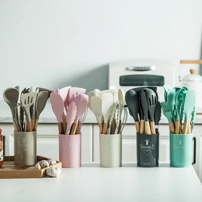 Set of silicone kitchen utensils with wooden handles in pastel pink beige black and teal with ceramic cup kitchen utensils set