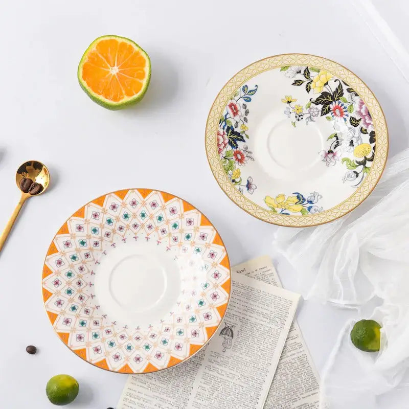 Two ceramic bone china coffee cup saucers with orange geometric and pastel floral patterns for tea time dining set