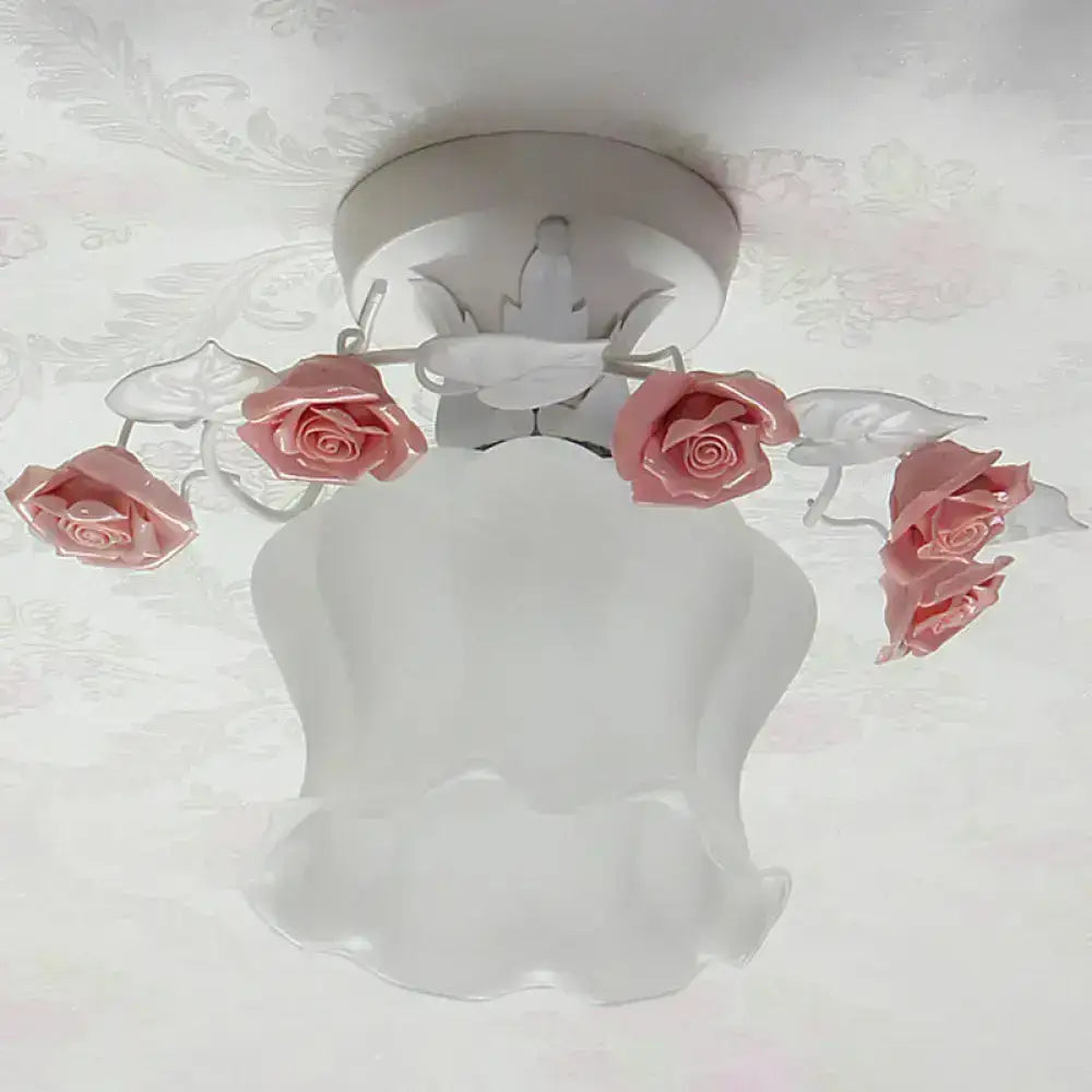 A delicate pink white glass semi flush dining room ceiling light fixture with rose-shaped ornaments and leafy accents