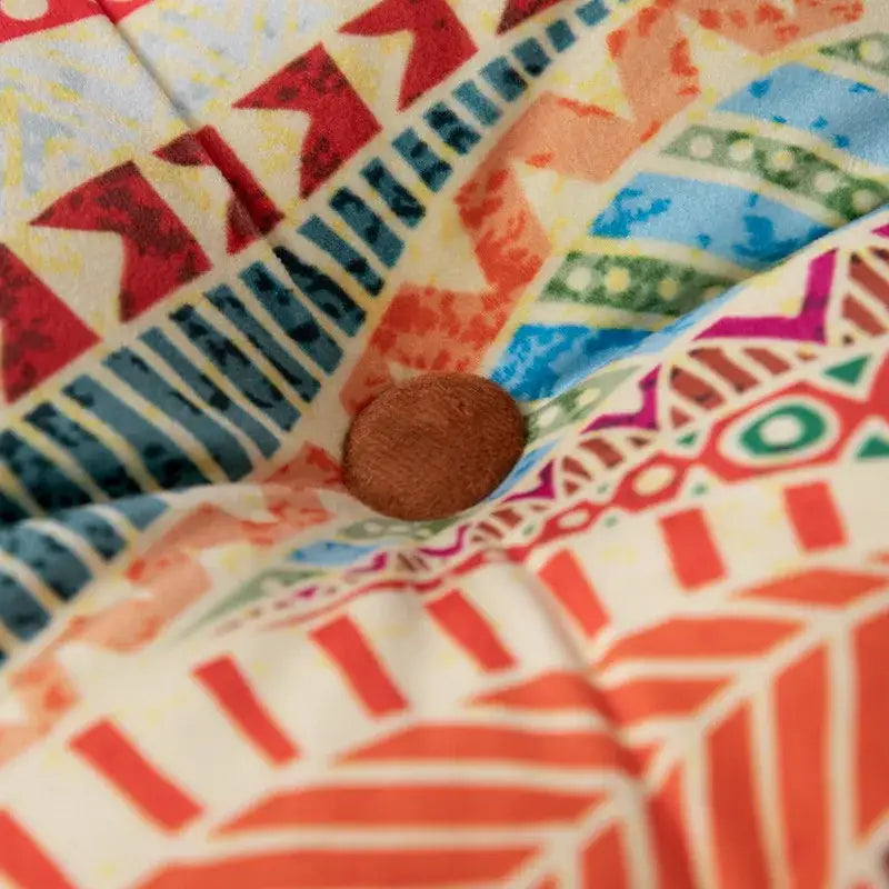 A round brown fabric button nestled in a vibrant bohemian mandala velvet floor cushion for reading nook decor
