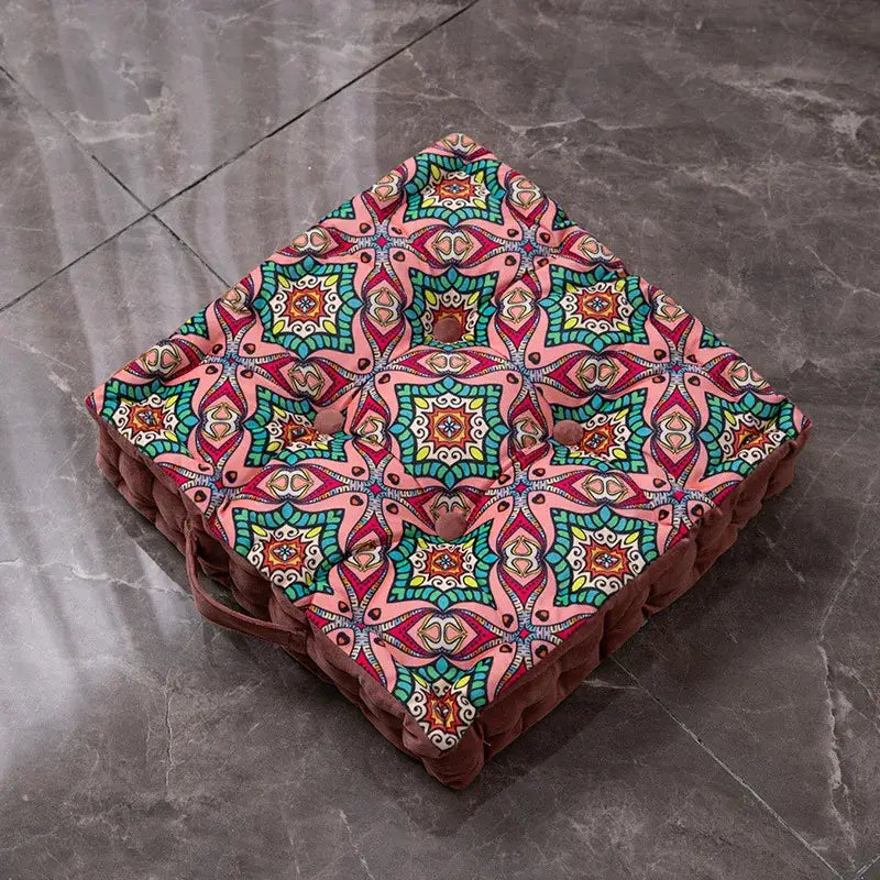 A square plush floor cushion with vibrant pink teal geometric pattern tufted buttons and brown fabric trim bohemian mandala velvet decor