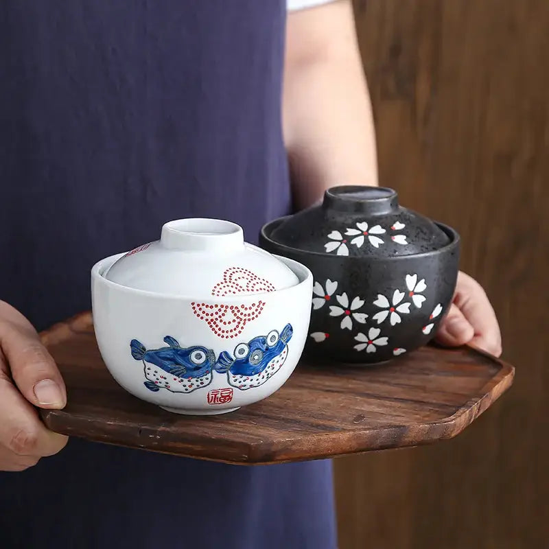 Patterned white and blue ceramic stew pot bowl with fish and red dot designs and matching lid for dining room use