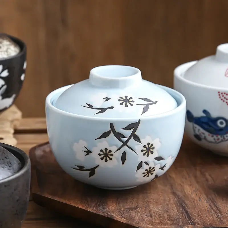 Light blue ceramic stew pot bowl with lid featuring delicate black and white floral birds and blossoms pattern