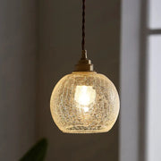A warm glowing decorbites pauline modern industrial ceiling light with crackled clear glass and brass hardware