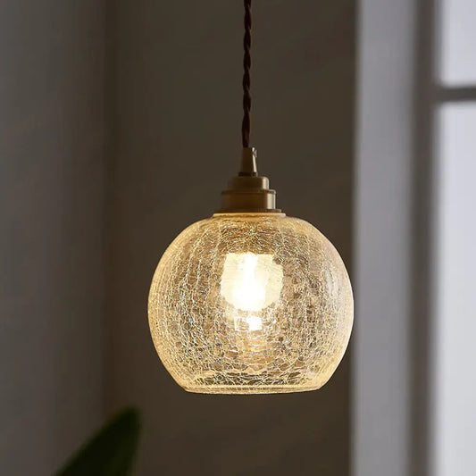 A warm glowing decorbites pauline modern industrial ceiling light with crackled clear glass and brass hardware