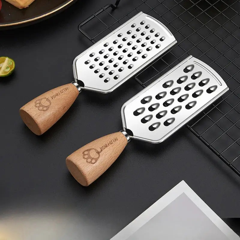 Two stainless steel multifunctional graters with wooden handles engraved with paw print and hello puppy text