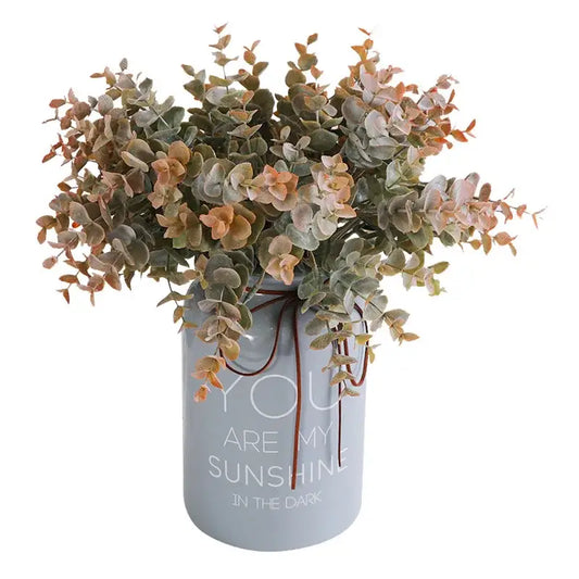 A light gray ceramic vase with you are my sunshine in the dark holding peach and green decorbites eucalyptus leaves artificial arrangement