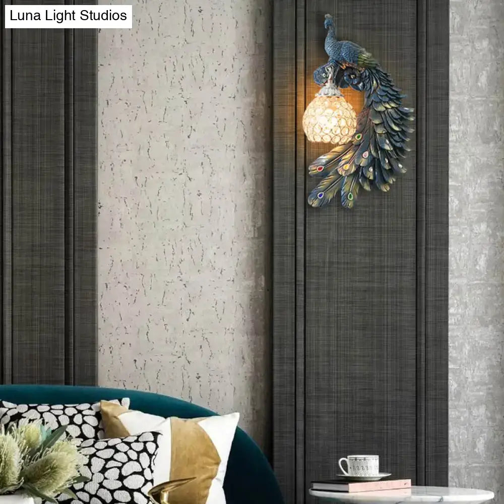 Peacock blue and gold wall sconce with metallic finish, intricate feather details, and clear crystal dome shade for bedroom lighting