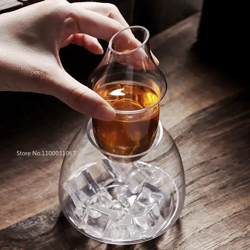 Pear shaped clear glass wine decanter and ice jug set with a bulbous base filled with amber liquid and ice