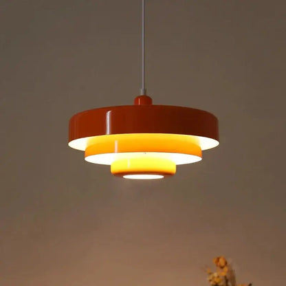 A modern bauhaus style pendant lighting with glossy orange outer ring and warm yellow inner rings on metallic rod