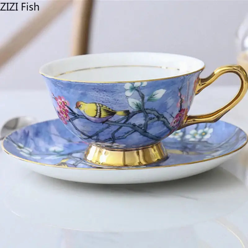 Blue porcelain teacup and saucer with gold trim and cartoon bird pattern featuring a painted yellow bird on branches