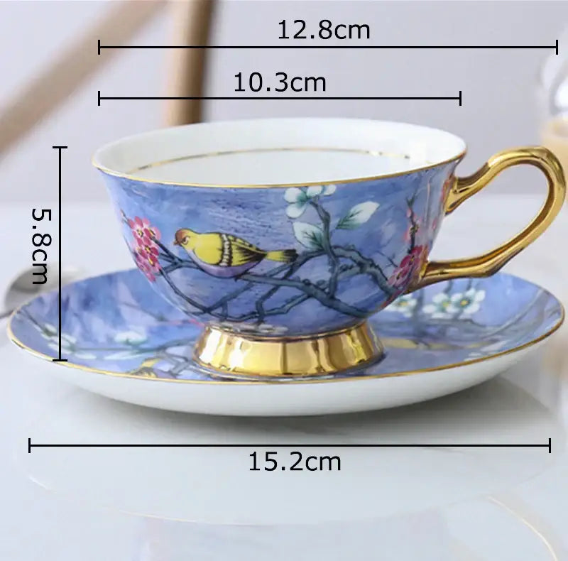 Blue porcelain teacup with gold trim and yellow cartoon bird pattern on blossoming branches with matching saucer