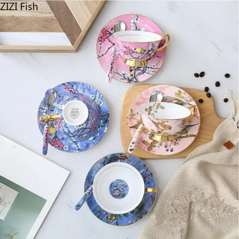 Pink and blue floral porcelain teacups with gold rims and matching saucers featuring a cartoon bird pattern
