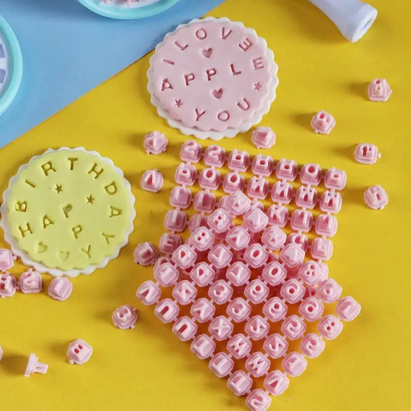 Pink and blue decorbites cookie stamps set with pink plastic letter stamps and two circular stamping plates for baking