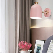 Pink dome-shaped wall light with brass-finished arm and mounting plate featuring a cup shade sconce lamp for dining rooms