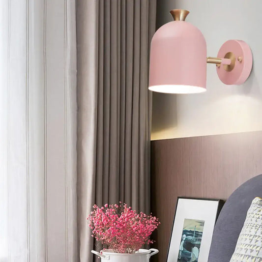 Pink dome-shaped wall light with brass-finished arm and mounting plate featuring a cup shade sconce lamp for dining rooms