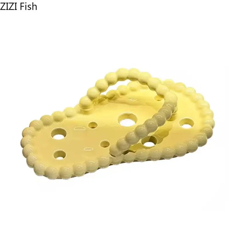 Yellow plastic cheese-shaped trivet with rounded edges and circular cutouts as a soap dish drainage rack accessory