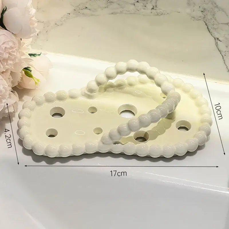 Cream-colored ceramic soap dish with scalloped edge and beaded handle as a soap dish drainage rack bathroom accessory