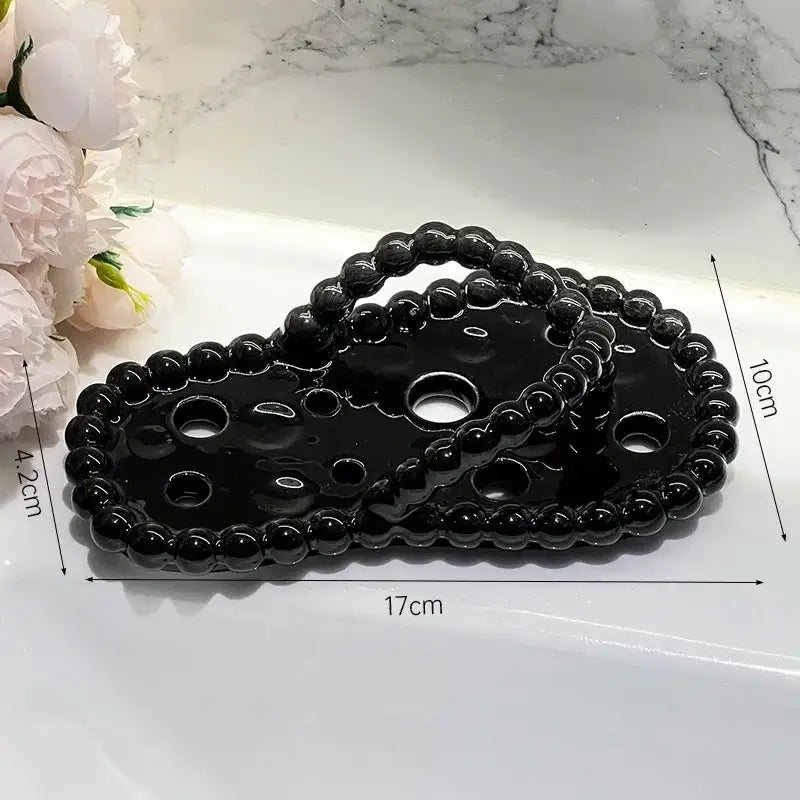 Black glossy ceramic heart-shaped tray with beaded edge and cutouts for use as a soap dish drainage rack accessory