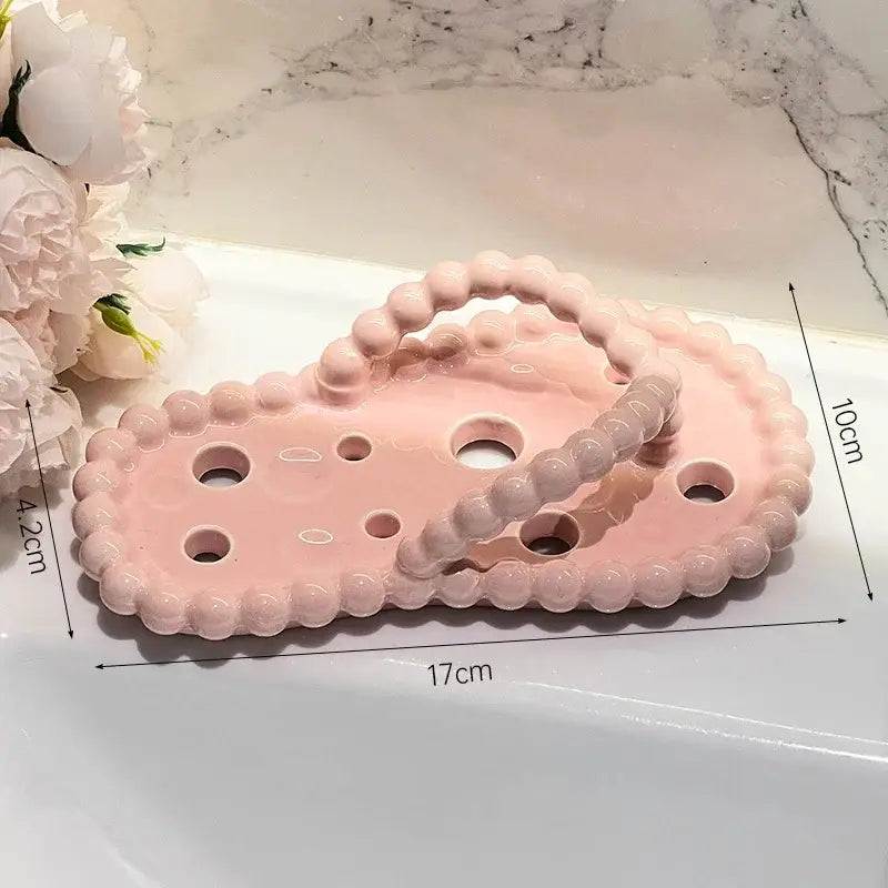 Pink ceramic soap dish drainage rack with scalloped edges and beaded handle for bathroom use