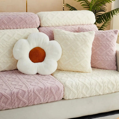 A plush white flower pillow with brown center on a pink and cream quilted velvet sofa cover seat protector