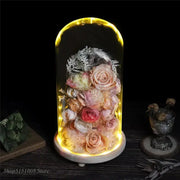 A glowing glass dome night light featuring pink and gold dry flower ornaments with preserved roses and foliage