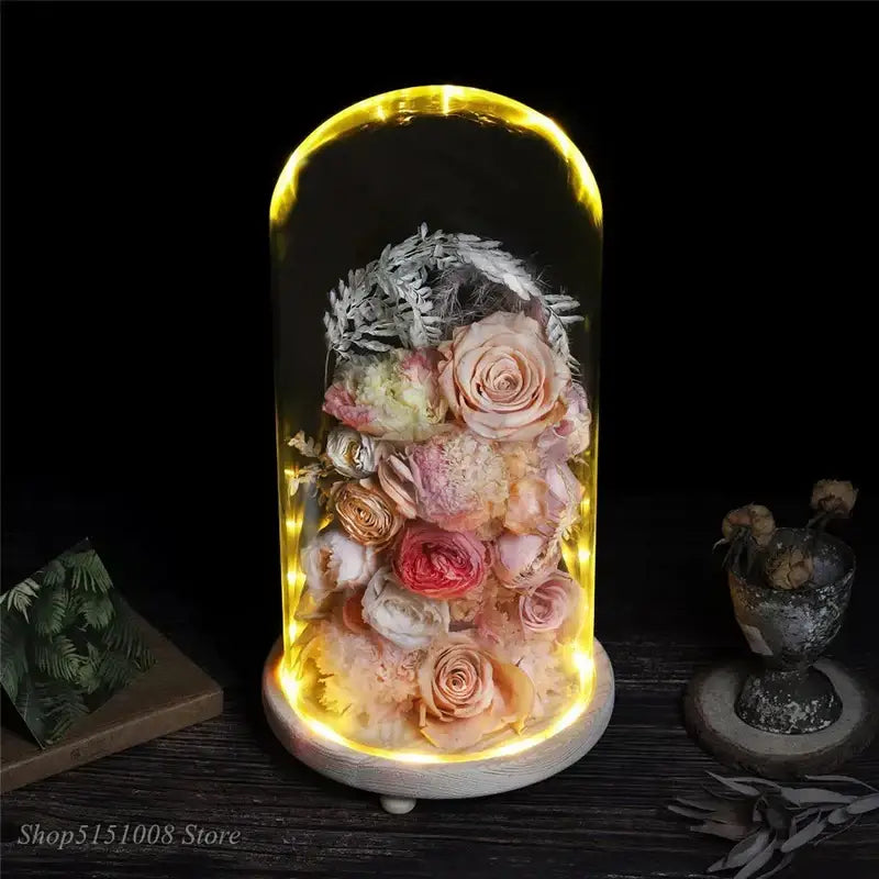 A glowing glass dome night light featuring pink and gold dry flower ornaments with preserved roses and foliage